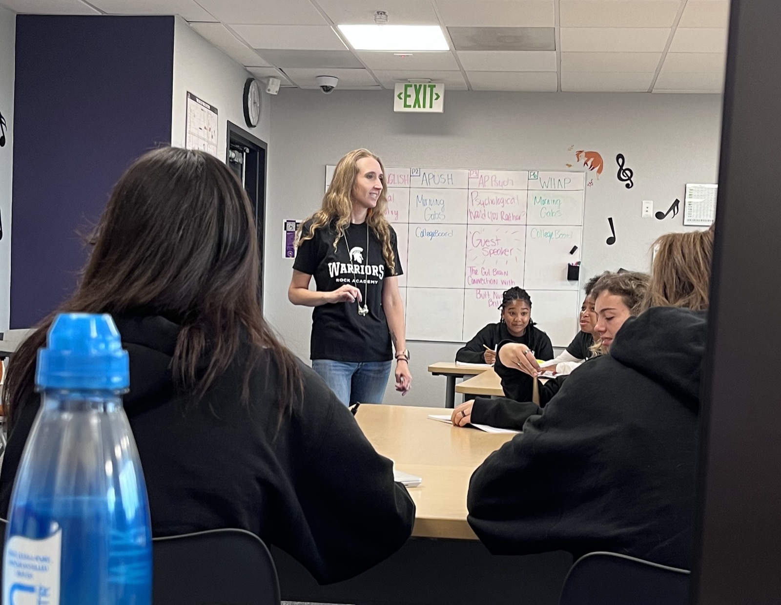 Taylor Fox teaching an AP class at the whiteboard, students seated around a shared table