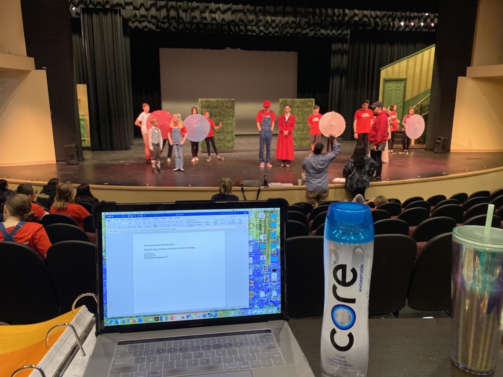 View from the director's table of a Mary Poppins rehearsal, laptop notes in the foreground