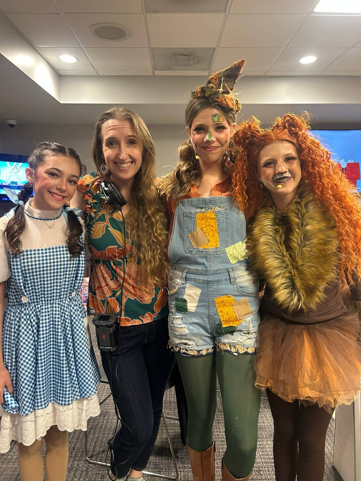 Taylor Fox backstage with students costumed as Dorothy, the Scarecrow, and the Lion